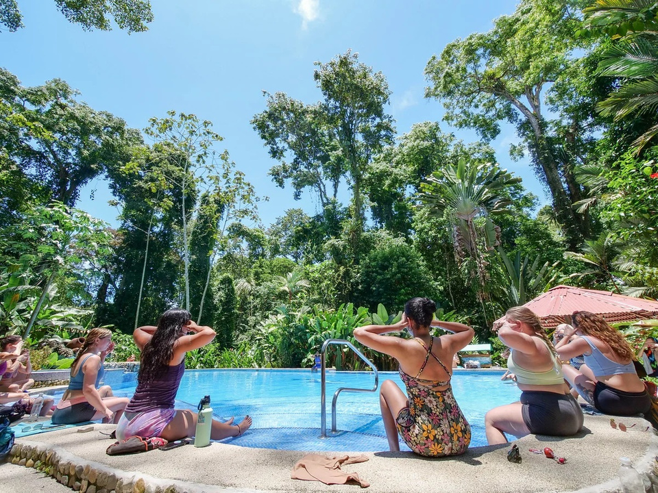 A yoga teacher group sits by the pool and practices asanas amidst the Costa Rican jungle